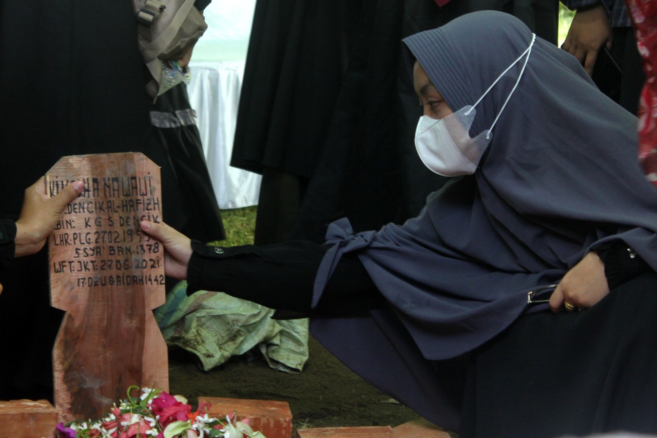 Seeorang santriwati Ponpes Ahlul Qur’an yang memegang nisan KH. Nawawi Dencik Al-Hafidz, senin (28/06). Foto: Rachman
